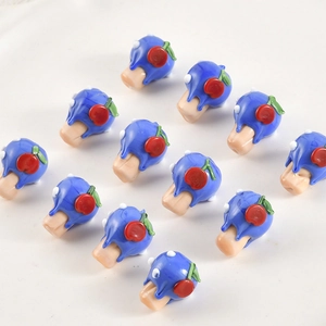 Macro detail of handmade lampwork beads featuring blue hair with red cherry accents