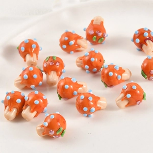 Macro detail of handmade orange mushroom glass beads with blue spots for DIY jewelry