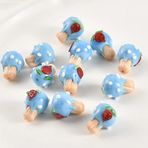 Detailed view of handmade lampwork mushroom beads with red strawberry and white polka dots