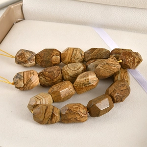 Close-up of faceted barrel-shaped natural jasper beads with earthy wood-like textures