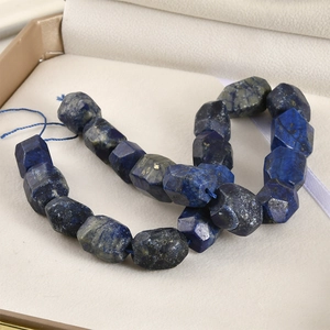 Macro shot of faceted blue lapis lazuli beads on a string inside a jewelry box