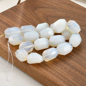 Macro detail of faceted semi-transparent white opal stone beads on dark wood