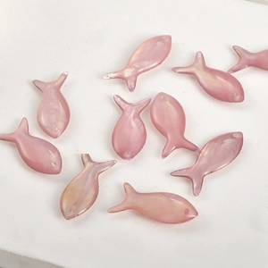 Macro view of pink iridescent fish-shaped pendants for DIY jewelry making and crafting