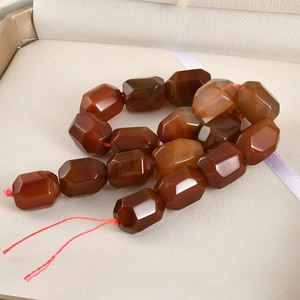 Macro detail of faceted red agate barrel beads with natural texture in jewelry box