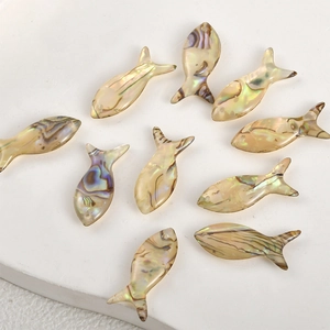 Macro shot of 11 fish-shaped natural abalone shell charms for DIY jewelry making