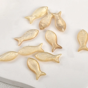 Macro view of fish-shaped natural shell beads with glossy luster for DIY jewelry making