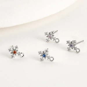 Close-up of snowflake cross earring studs with colored zircon centers for DIY jewelry