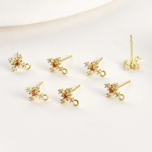Detailed macro view of 14k gold plated cross snowflake earring charms with orange zircon