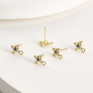 Macro detail of 14k gold plated cross star earring studs with blue zircon for DIY jewelry