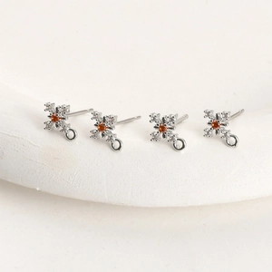 Macro detail of silver snowflake charms with orange zircon center for DIY jewelry making
