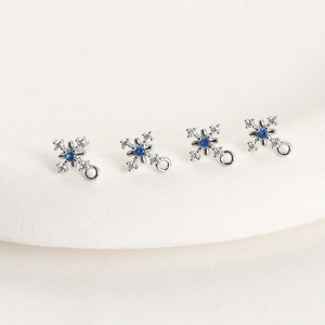 Detailed macro view of four snowflake charms with white cubic zirconia and blue center stones