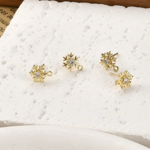 Vista macro di quattro ciondoli a fiocco di neve placcati oro 14k con zirconi per DIY