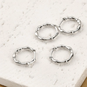 Vue macro de boucles d'oreilles argentées ondulées sur une base en pierre blanche
