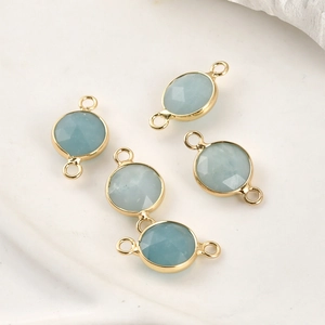 Detail of light blue faceted crystal charms with gold-plated double rings for DIY jewelry