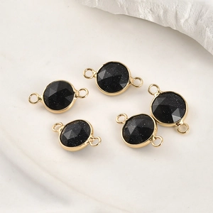 Close-up of faceted blue sandstone round charms with gold-plated connectors for jewelry