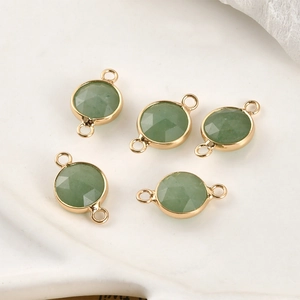 Macro view of natural green gemstone round connectors featuring faceted gold-plated bezels