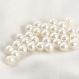 Dettaglio di perle bianche finte con fori preforati per la creazione di gioielli fai da te