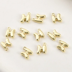 Dettaglio di ciondoli a forma di lettera H placcati in oro 14k per gioielli fai-da-te