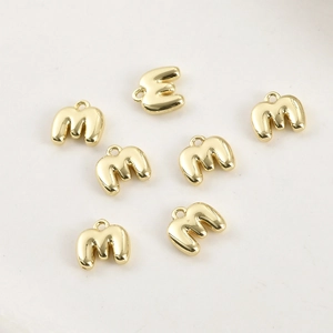 Dettaglio dei ciondoli a lettera M in rilievo placcati oro 14k con anelli di chiusura