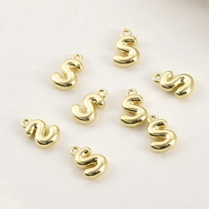 Dettaglio di ciondoli a lettera S placcati oro 14k con occhielli per creazione di gioielli