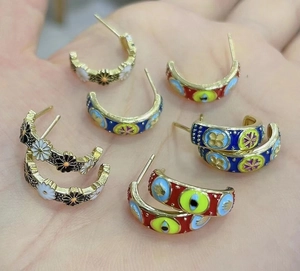 Detail of vintage enamel hoop earrings with daisy and evil eye patterns in various colors
