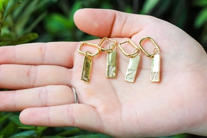 Gold letter earrings featuring micro-pave initials in rectangular frames on palm
