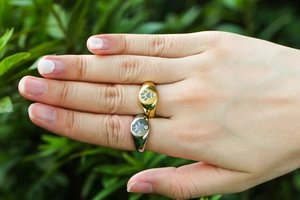 Gold and silver footprint signet rings with zircon, displayed on fingers outdoors