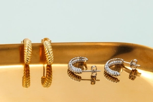 Eleganti orecchini a cerchio intrecciati oro e argento su vassoio per stile quotidiano