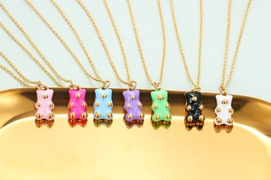 Detail of seven colorful enamel bear pendants with gold chains on a metal tray