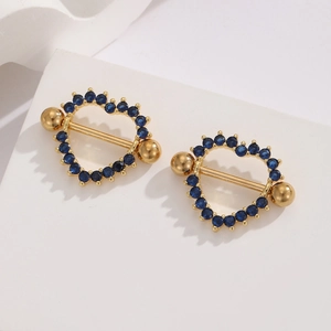 Close-up of golden stainless steel heart nipple rings with deep blue zircon pave detail