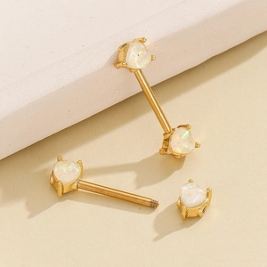Macro detail of 18K gold stainless steel heart opal nipple rings with screw threads