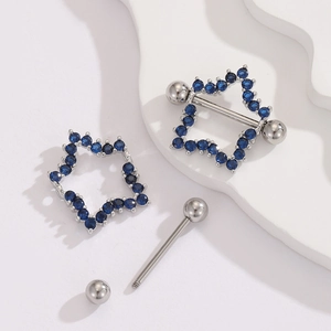 Detailed view of 18K gold star nipple ring set with blue cubic zirconia on a white plate