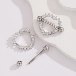 Macro shot of stainless steel heart nipple ring with clear zircon inlay on white marble