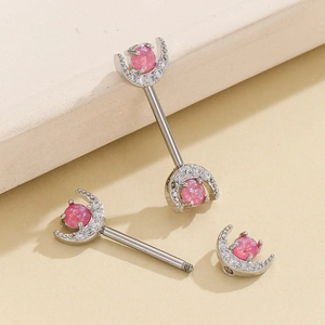 Macro view of moon-shaped nipple rings with pink gemstones and inlaid white crystals