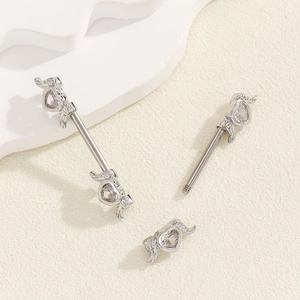 Detail of silver nipple bar featuring heart-shaped rhinestones and mini wing accents