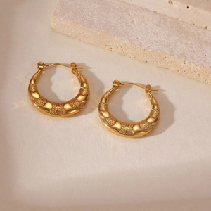 Macro view of 18K gold plated hoop earrings with embossed cross and diamond textures