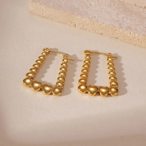 Dettaglio ravvicinato di orecchini a trapezio placcati oro 18k con texture a cuoricini