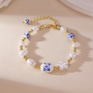 Close-up of blue floral porcelain beads and pearls with a golden lobster clasp detail