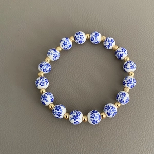 Dettaglio macro del bracciale di perline in porcellana blu e bianca con distanziatori oro
