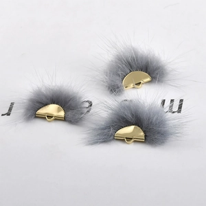 Close-up of gray mink fur fan-shaped pendants with golden metal loops for DIY jewelry