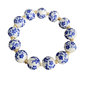 Bracciale di perle in porcellana bianca e blu con distanziali dorati su bianco
