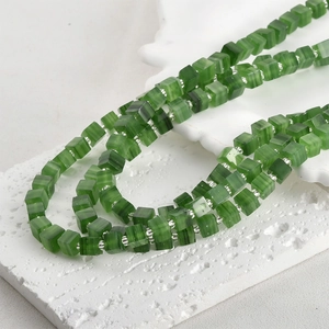 Macro shot of 6mm green sugar cube glass beads with cat eye effect and silver spacers