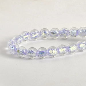 Dettaglio macro di perle tonde in vetro iridescente viola blu per creazione gioielli fai da te