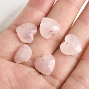 Hand holding five faceted pink quartz heart pendants with pre-drilled holes for DIY jewelry