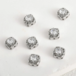 Macro shot of silver square spacer beads with white zircon and filigree for DIY jewelry