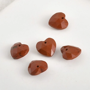 Macro detail of red jasper heart charms with geometric facets and pre-drilled holes