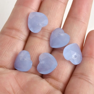 Macro view of 13mm light blue faceted heart-shaped crystal beads held in hand for DIY jewelry