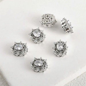 Macro detail of 14k silver plated copper beads with oval zircon and hollow flower patterns