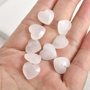 Macro detail of 13mm faceted heart-shaped natural crystal beads held in hand for DIY jewelry