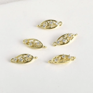 Dettaglio macro di ciondoli a foglia placcati oro 14k con tre zirconi bianchi e motivi traforati